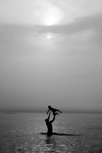 Père et fils nageant dans la mer au coucher du soleil — Photo