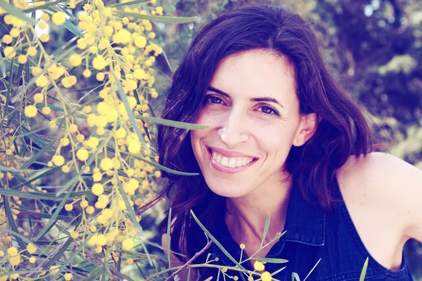 Sarı çiçekli dışarıda gülümseyen kadın portresi — Stok fotoğraf