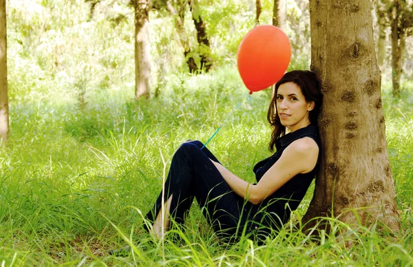 Beautiful woman with red balloon in the park — Stock Photo, Image