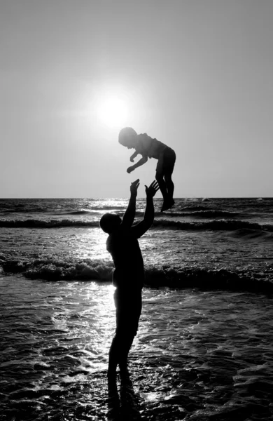 Pai e filho no mar ao pôr do sol — Fotografia de Stock