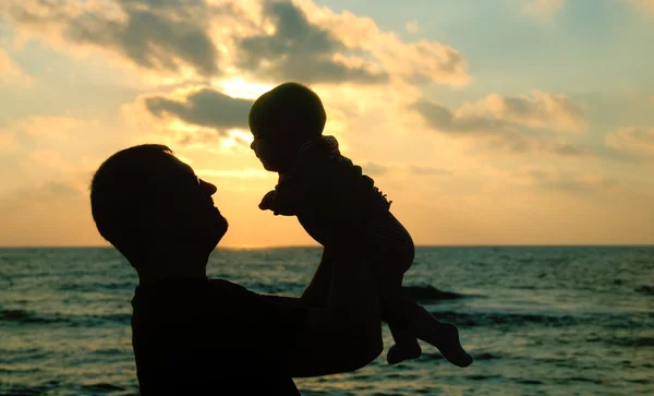 Pai e filha brincando na praia ao pôr do sol — Fotografia de Stock