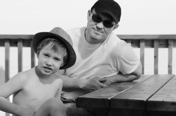 Feliz padre y su hijo sentados en la cafetería de verano en la playa — Foto de Stock