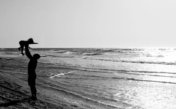 Ojciec z dzieckiem na plaży o zachodzie słońca — Zdjęcie stockowe