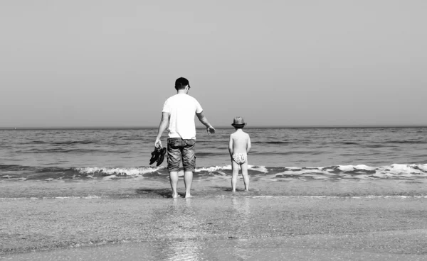 Far och son ska bada i havet. svartvitt foto. — Stockfoto