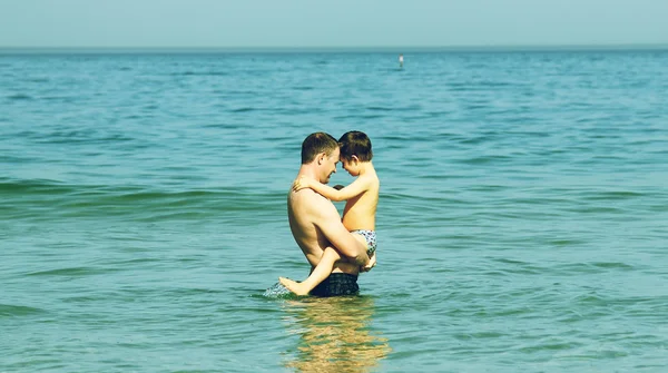 Vader en zoon zwemmen in de zee. zwart / wit foto. — Stockfoto