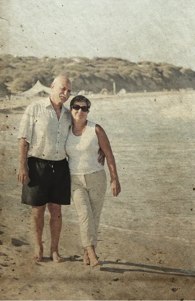 Happy senior couple walking together on a beach. Photo in old im — Stock Photo, Image