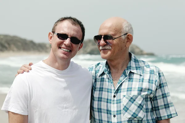 Hijo adulto y padre caminando juntos en la playa — Foto de Stock