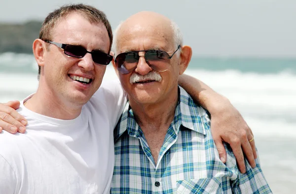 Hijo adulto y padre caminando juntos en la playa — Foto de Stock