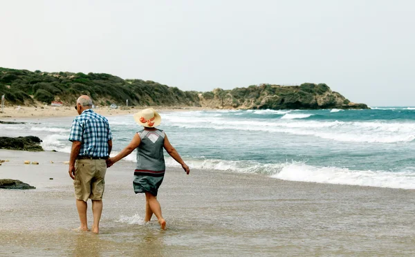 Backview van senior koppel wandelen op zandstrand — Stockfoto