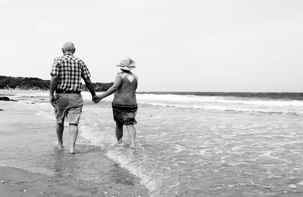 Felice coppia anziana che cammina insieme su una spiaggia — Foto Stock