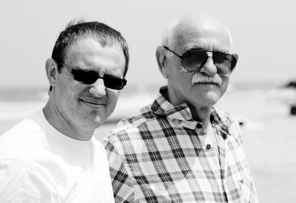 Hijo adulto y padre caminando juntos en la playa — Foto de Stock