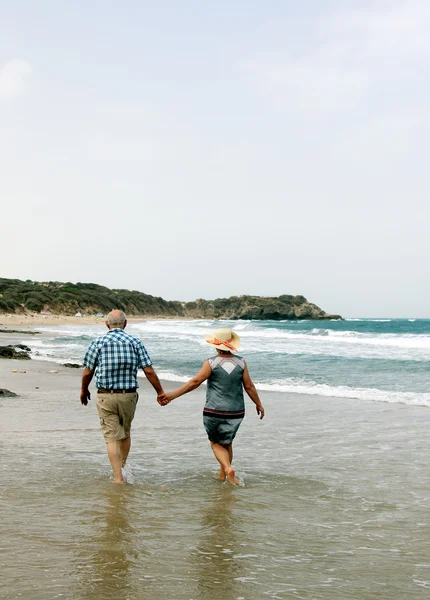 Backview pary seniorów spacerujących po piaszczystej plaży — Zdjęcie stockowe