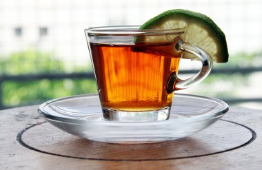 ahşap masa üzerinde duran limon ile çay