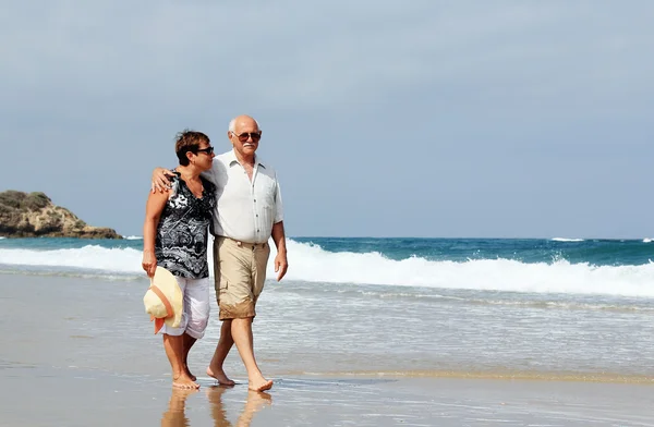 Gelukkige senior paar lopen samen op een strand — Stockfoto
