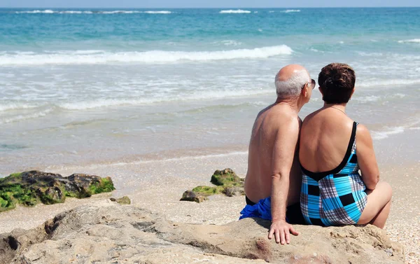 Portret szczęśliwy senior para siedzi razem na plaży — Zdjęcie stockowe