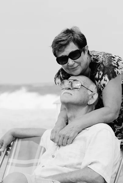 Retrato de casal de idosos felizes sentados juntos em uma praia — Fotografia de Stock