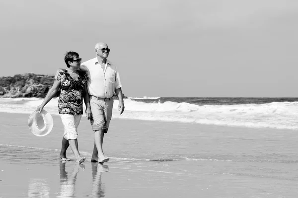 Lyckliga äldre par promenader tillsammans på en strand — Stockfoto