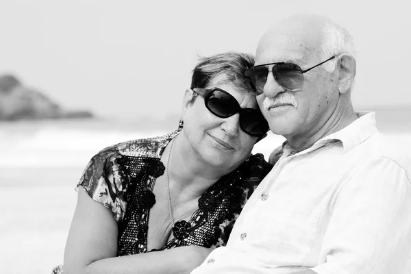 Retrato de casal de idosos felizes sentados juntos em uma praia — Fotografia de Stock