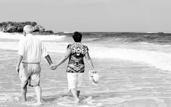 Gelukkige senior paar lopen samen op een strand — Stockfoto