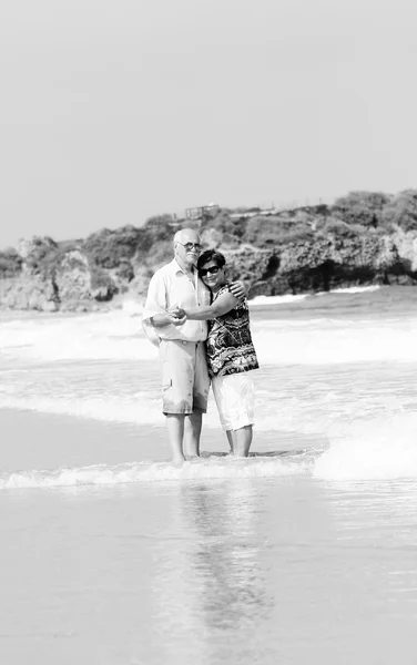 Feliz pareja de ancianos caminando juntos en una playa — Foto de Stock