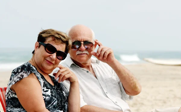 Portret szczęśliwy senior para siedzi razem na plaży — Zdjęcie stockowe