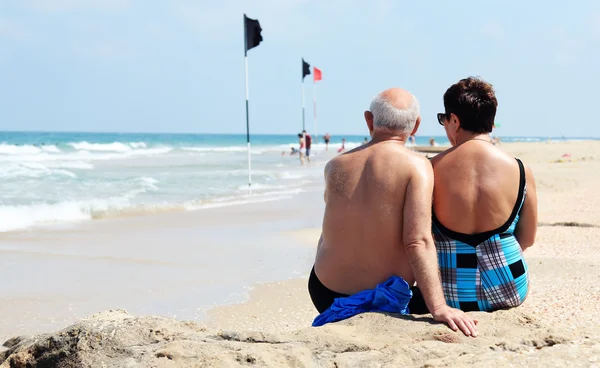 Retrato de feliz pareja de ancianos sentados juntos en una playa —  Fotos de Stock