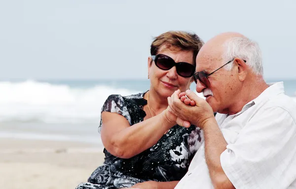 Портрет счастливой пожилой пары, сидящей вместе на пляже — стоковое фото