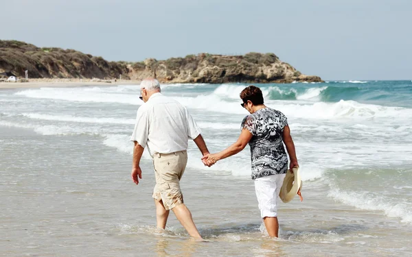 Feliz pareja de ancianos caminando juntos en una playa — Foto de Stock