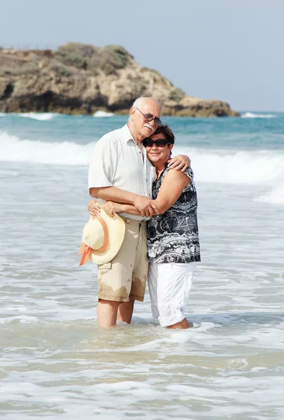 Gelukkige senior paar lopen samen op een strand — Stockfoto