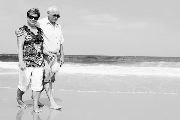 Feliz pareja de ancianos caminando juntos en una playa — Foto de Stock