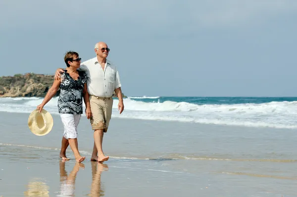 Casal sênior feliz andando juntos em uma praia — Fotografia de Stock