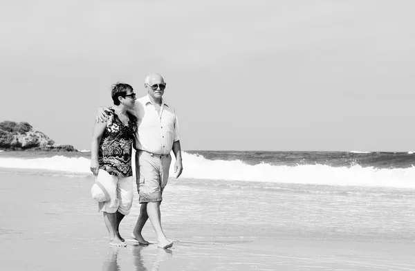 Lyckliga äldre par promenader tillsammans på en strand — Stockfoto