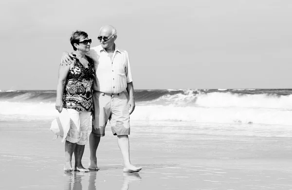 Lyckliga äldre par promenader tillsammans på en strand — Stockfoto