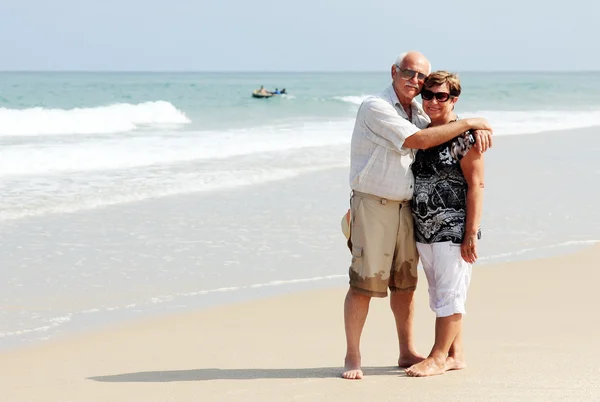 Casal sênior feliz andando juntos em uma praia — Fotografia de Stock