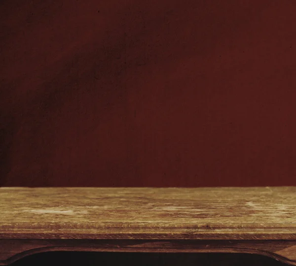 Винтажный фон с деревянным столом и тертой красной стеной — стоковое фото