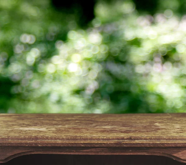Vintage wooden table with foliage bokeh background — Stock Photo, Image