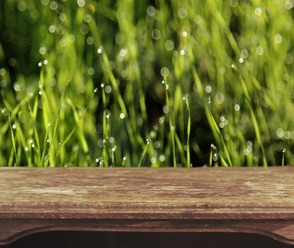 Vintage wooden table with foliage bokeh background — Stock Photo, Image