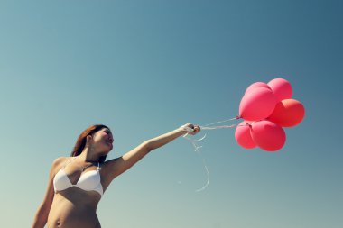 Kırmızı balonlar tutan genç hamile kadın