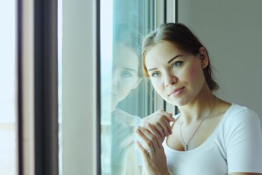 güzel kadın pencerenin önünde duruyor.