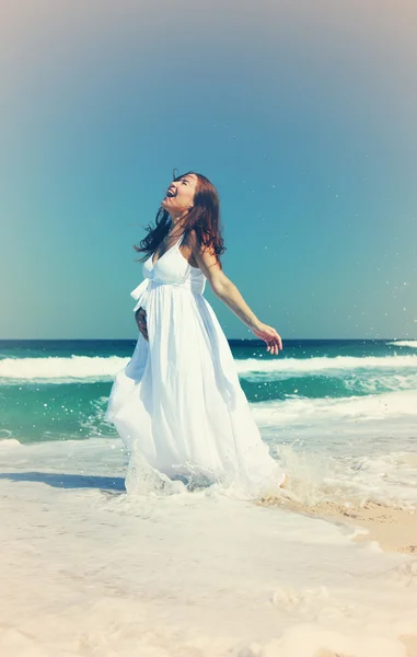 Jovem mulher sorridente em vestido branco de pé em ondas do mar — Fotografia de Stock