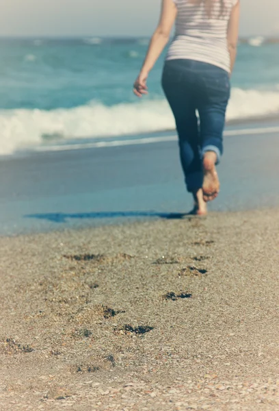 Giovane donna che cammina sulla spiaggia. Concentrati sulla sabbia . — Foto Stock