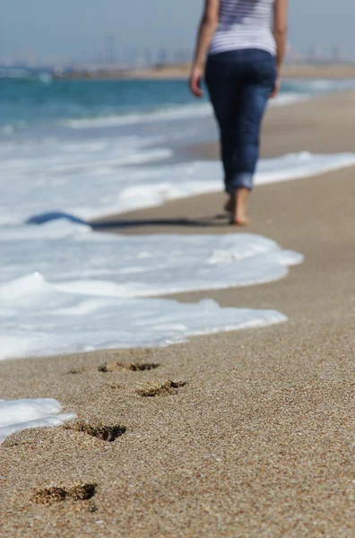 Νεαρή γυναίκα που περπατούν στην παραλία. επικεντρωθεί στην άμμο. — Φωτογραφία Αρχείου