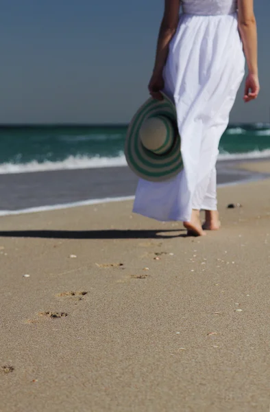 Młoda kobieta w białej sukni spaceru na plaży — Zdjęcie stockowe