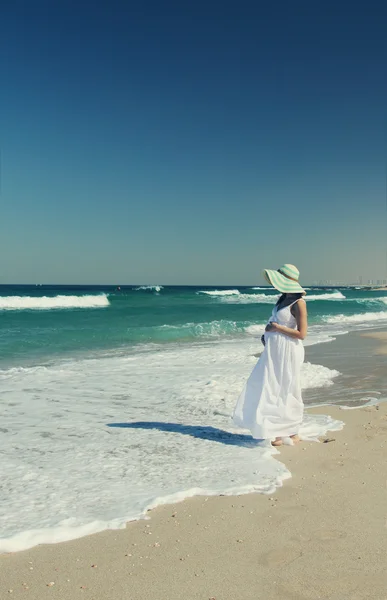 Mujer embarazada joven caminando en la playa — Foto de Stock