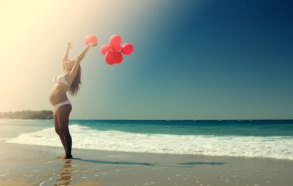 Junge schwangere Frau mit roten Luftballons — Stockfoto