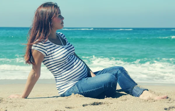 Piękna kobieta w ciąży, siedząc na plaży — Zdjęcie stockowe