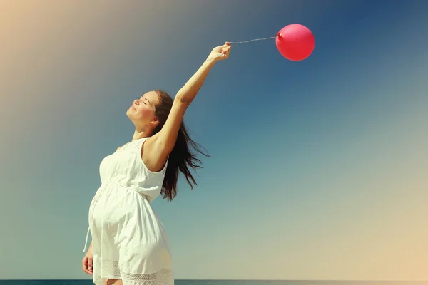 Mooi meisje met rode ballon bij blauwe hemelachtergrond — Stockfoto