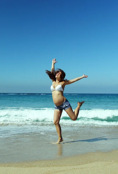 Hermosa mujer embarazada saltando en la playa — Foto de Stock