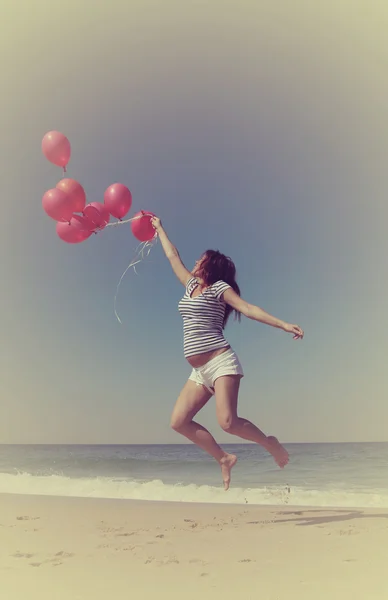Mooi meisje met rode ballonnen bij blauwe hemelachtergrond — Stockfoto