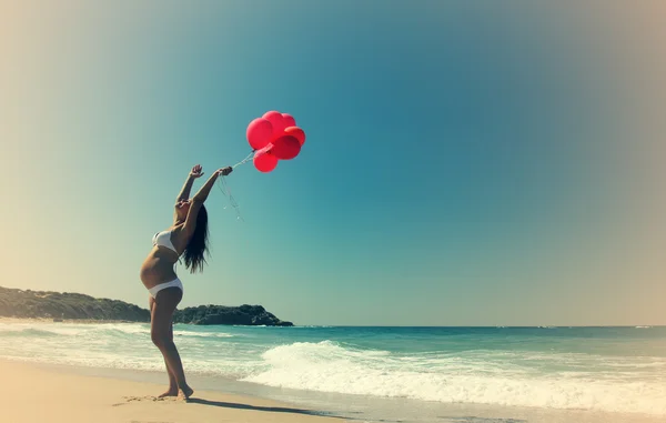 Kırmızı balonlar tutan genç hamile kadın — Stok fotoğraf